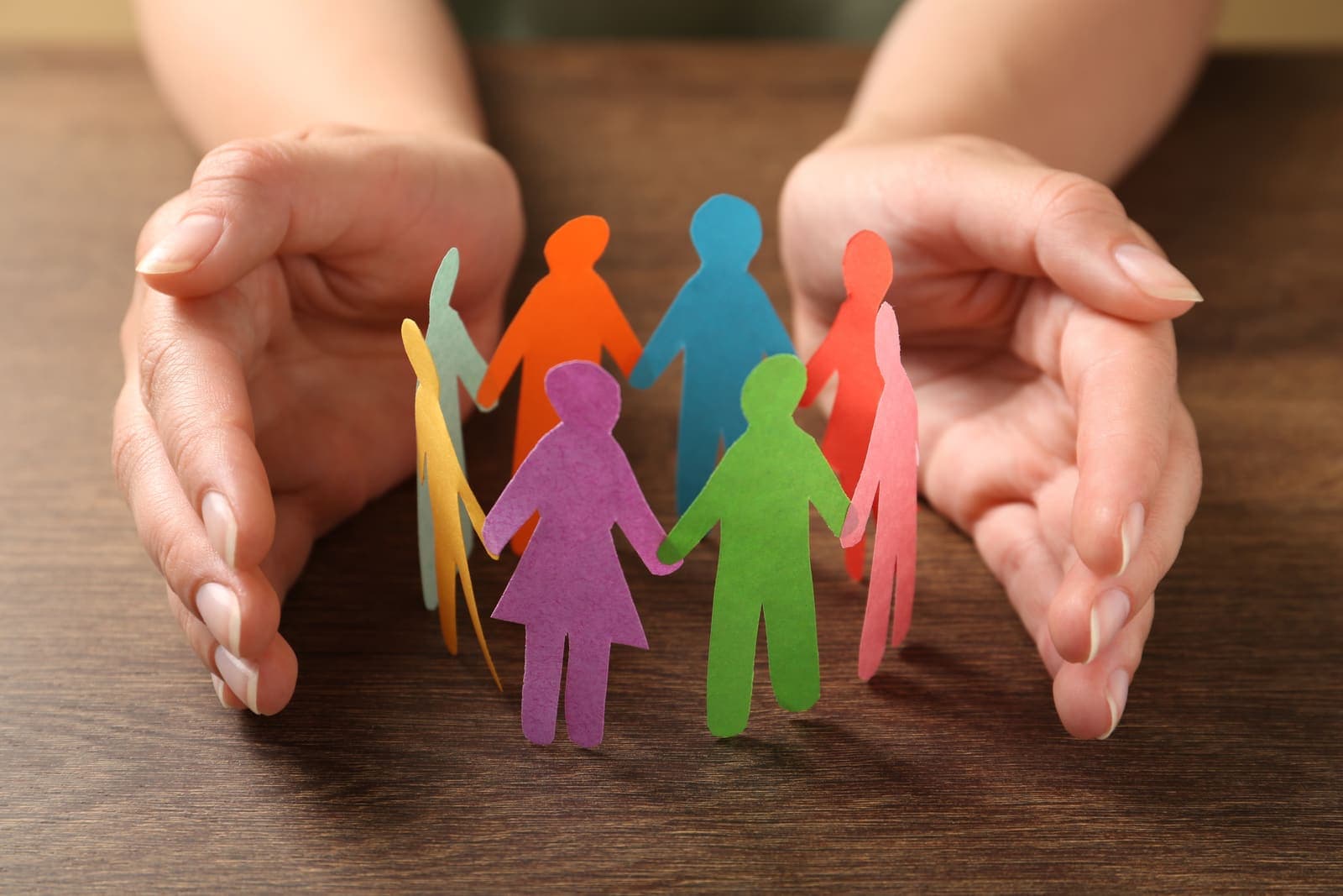 Beschermende hand boven papieren figuren