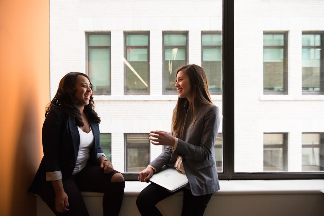 Twee collega's in een open, vertrouwd gesprek bij het raam